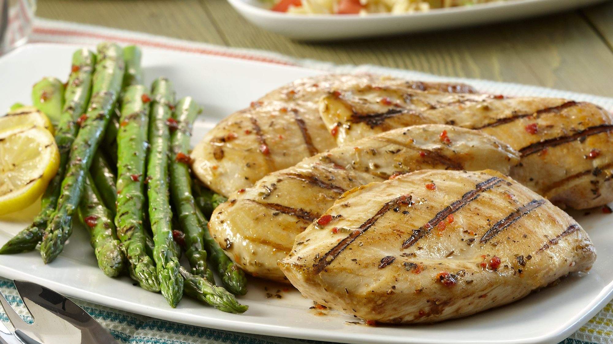 Grilled chicken and asparagus with lemon slice.